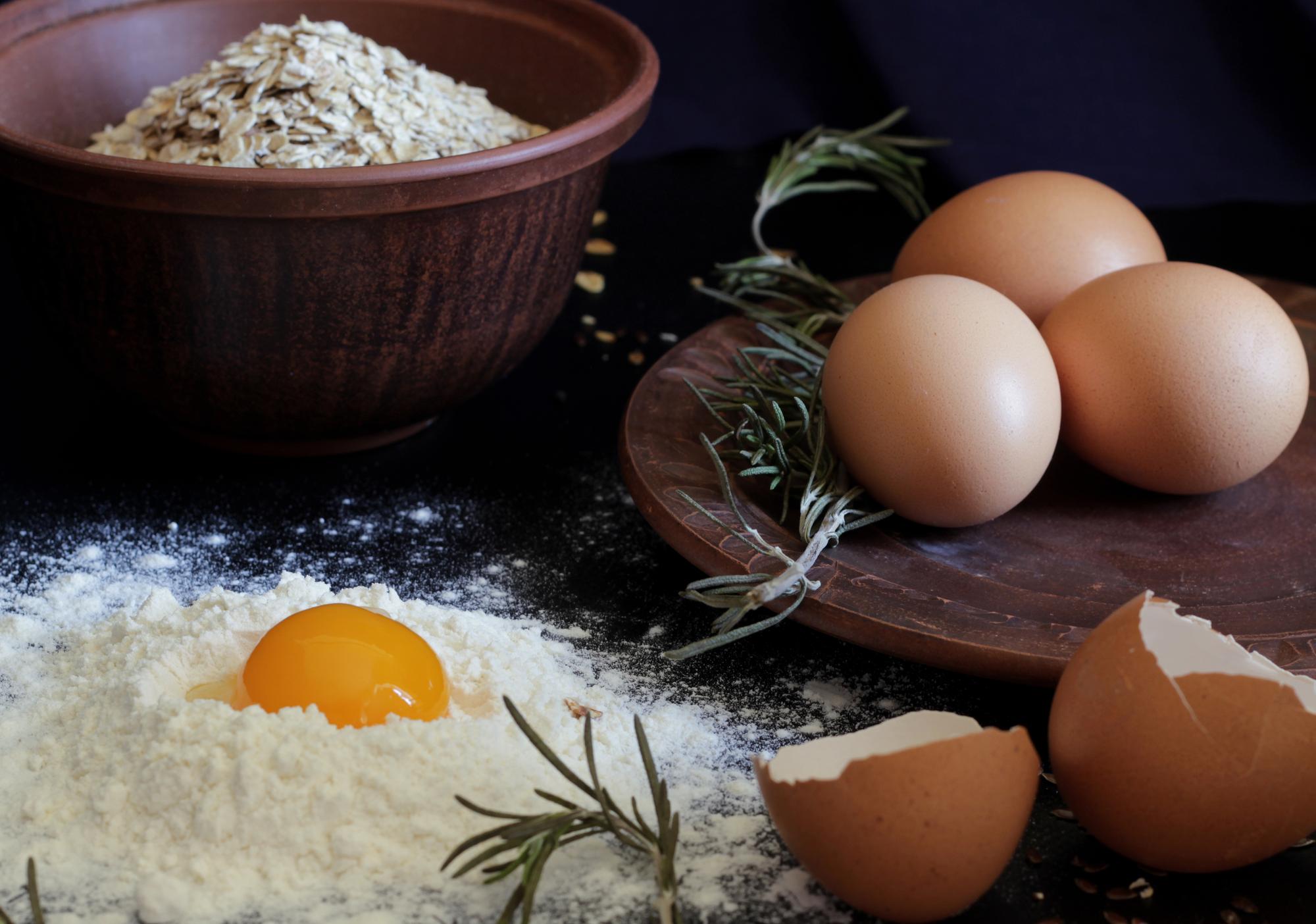 Close-up of herbs, eggs and flour on wooden table